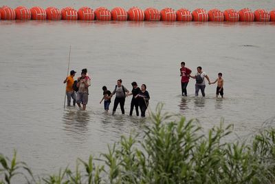 In a showdown Texas' floating border barrier, the governor tells Biden: `See you in court'