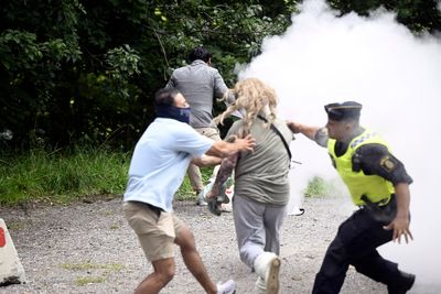 A woman interrupts a Quran-burning protest in Sweden by spraying activist with a fire extinguisher