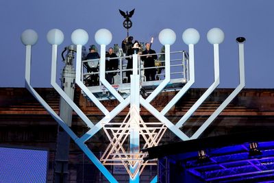 Germany's chancellor lights first Hanukkah candle on a huge menorah at Berlin's Brandenburg Gate