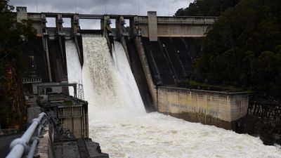 Largest dam spills, but axed wall extension defended
