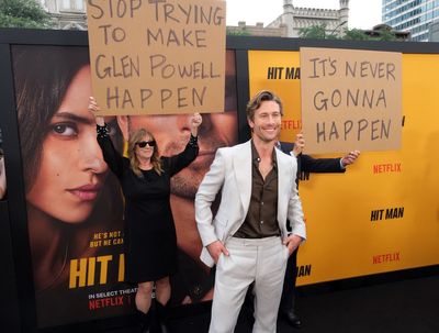 Glen Powell’s parents hilariously troll him with signs on Hit Man red carpet