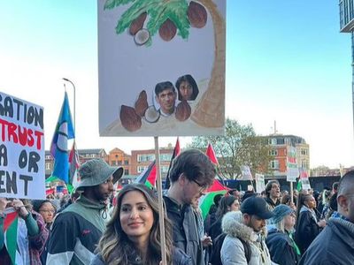 Woman who carried placard depicting Sunak and Braverman as coconuts charged with hate crime