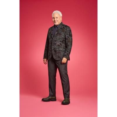 Tom Jones Stuns In Timeless Black Against Vibrant Pink Backdrop