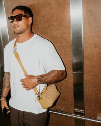 James Conner's Stylish Look: White Tee, Sunglasses, Beige Bag