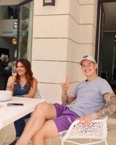 James Rodríguez And Girlfriend Seated On White Chairs Together