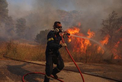 A wildfire near Greece's capital darkens the skies over Athens and advances fast