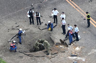 A US bomb from World War II explodes at a Japanese airport, causing a large crater in a taxiway