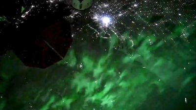 ISS astronaut captures green auroras dancing over city lights (video)