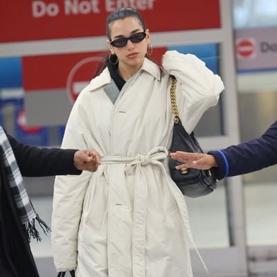 Dua Lipa's Maximalist Airport Outfit Pairs a Sleeping Bag Coat and Puma Sneakers with Chanel and a Tricked-Out Birkin