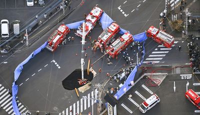 Families near Japan sinkhole asked to evacuate as truck driver remains trapped