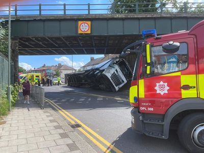Lorry overturns after crashing into railway bridge in south London
