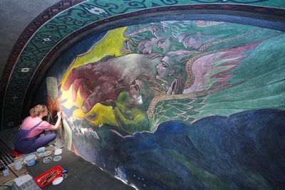 Inside a historic church painted with murals that reflect searing social commentary