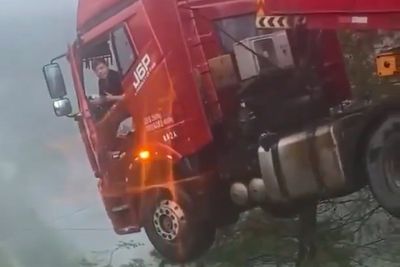 Watch: Lorry driver left dangling over edge of 700ft collapsed bridge after landslide