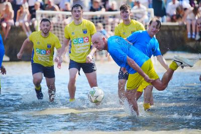 Traditional river football match goes ahead despite waterlogged pitch