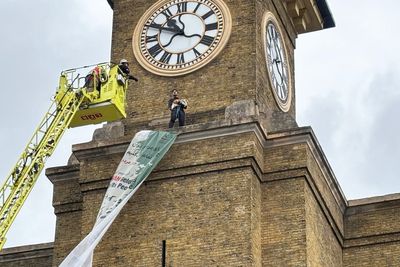 Protester carrying dog scales clock tower at King’s Cross station