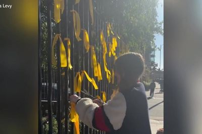 Woman cuts down yellow ribbons commemorating Israeli hostages