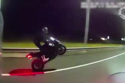 Speeding motorcyclist performs wheelie not realising police are right behind him