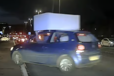 Passenger clings to sofa balancing precariously on car’s roof