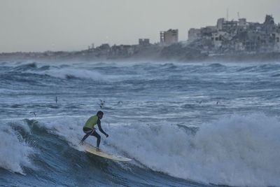 Photos show surfers riding waves along Gaza City’s damaged coastline
