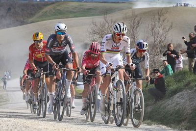 Why do the riders compete on road bikes at Strade Bianche, not gravel bikes?