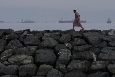 Photos of beachgoers in UAE where oil tankers and cargo ships line up in Hormuz Strait