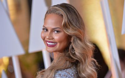 Yes, Beige Can Still be Chic – Chrissy Teigen Elevates the Warm Neutral Color Scheme With Floral Pillows, a Pink Throw Blanket, and Gold Accents