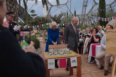 King and Queen laugh as they struggle to cut cake with sword