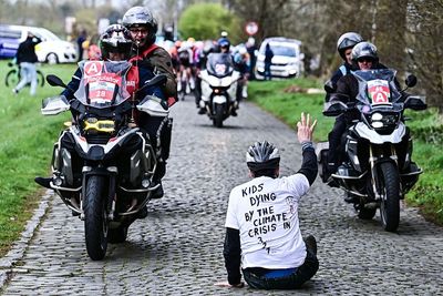 Climate protester sits down on cobbles in front of oncoming peloton at Ronde Van Brugge