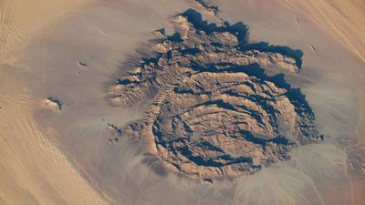 Concentric rocky rings adorned with ancient artwork wear a magma 'hat' in the Sahara — Earth from space