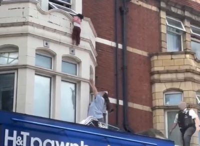 Terrifying moment child clings to window ledge above London high street shop before dramatic rescue