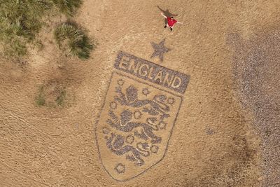 Artist crafts England badge on beach as World Cup campaign nears kick-off