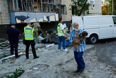 Photos show Kyiv residents clutching pets, collecting bodies after Russian missile and drone attack