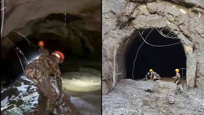 Teams, equipped with searchlights and drones, walk through mud, silt to search for survivors in tunnels