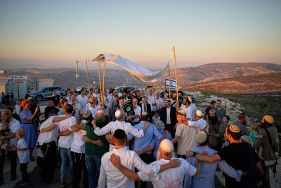 Israeli settlers, some armed, celebrate a new synagogue in the occupied West Bank, in photos