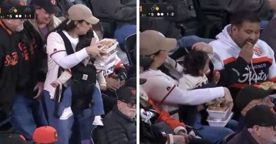 Dad Digs Into His Food While Mom Handles Their Baby And Everything Else At The Giants Game