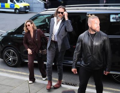 Russell Brand flanked by security as he arrives at London court for rape and sex assault trial