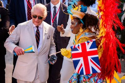Charles shakes maracas and joins dancers in carnival parade